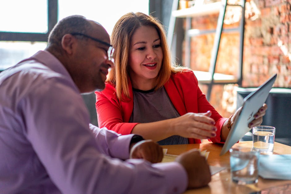 Two adults engaged in a productive conversation using a tablet in a modern office setting.